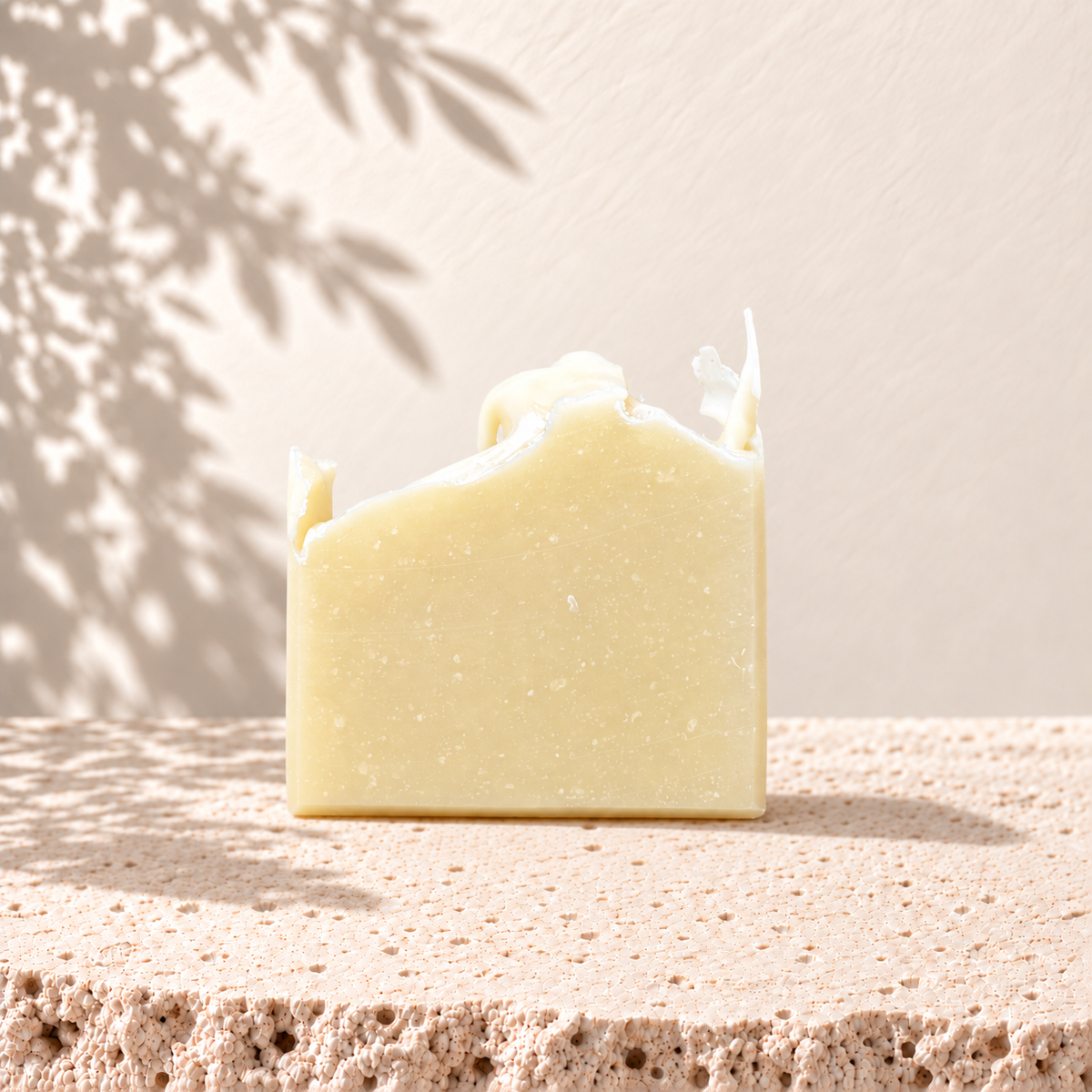 Savon naturel beige avec texture rugueuse sur fond neutre ombragé.