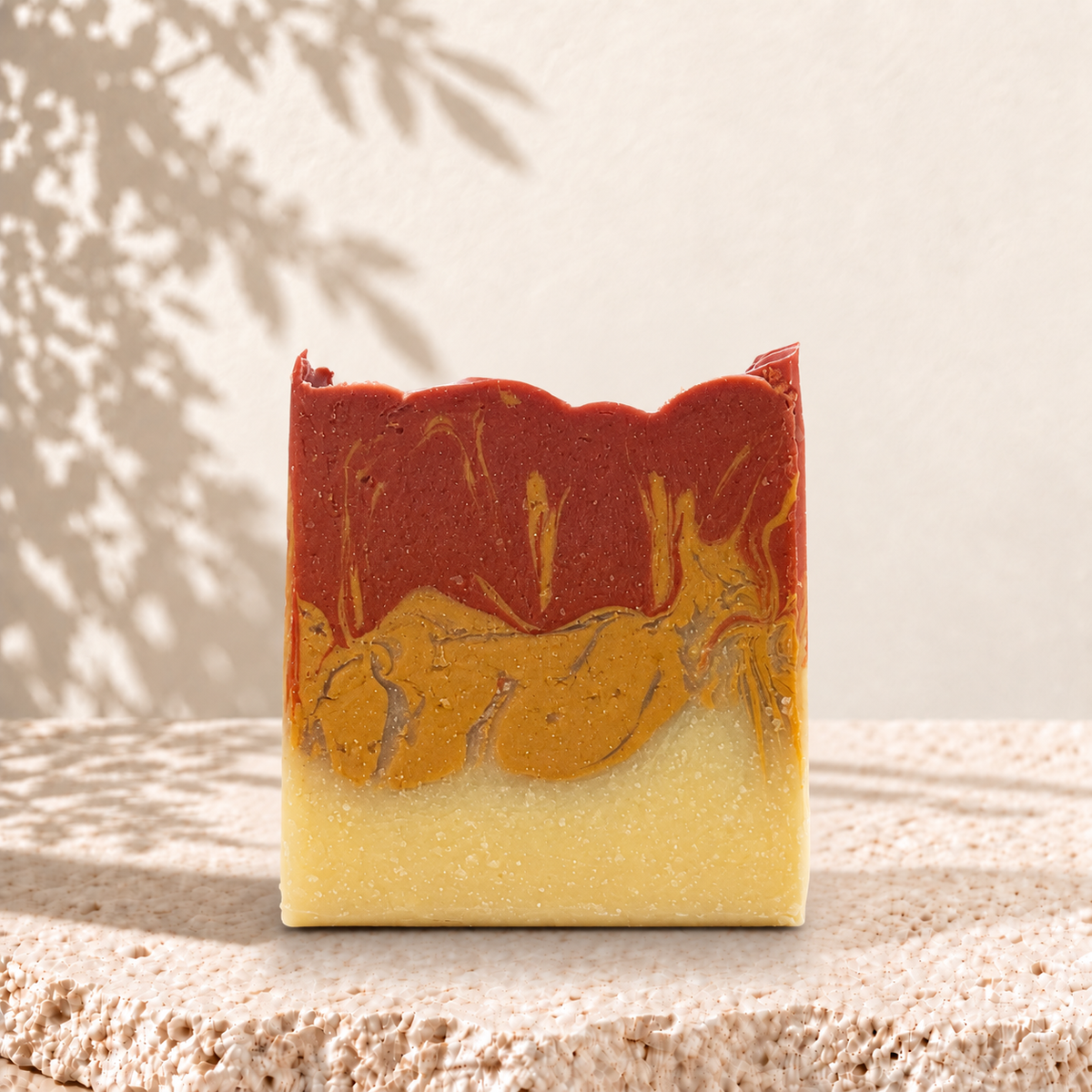 Savon artisanal bicolore rouge et jaune à l'argile, forme irrégulière, texture naturelle.