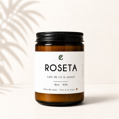Bougie en verre ambré avec étiquette blanche minimaliste, parfum lait de riz et santal, couvercle noir.