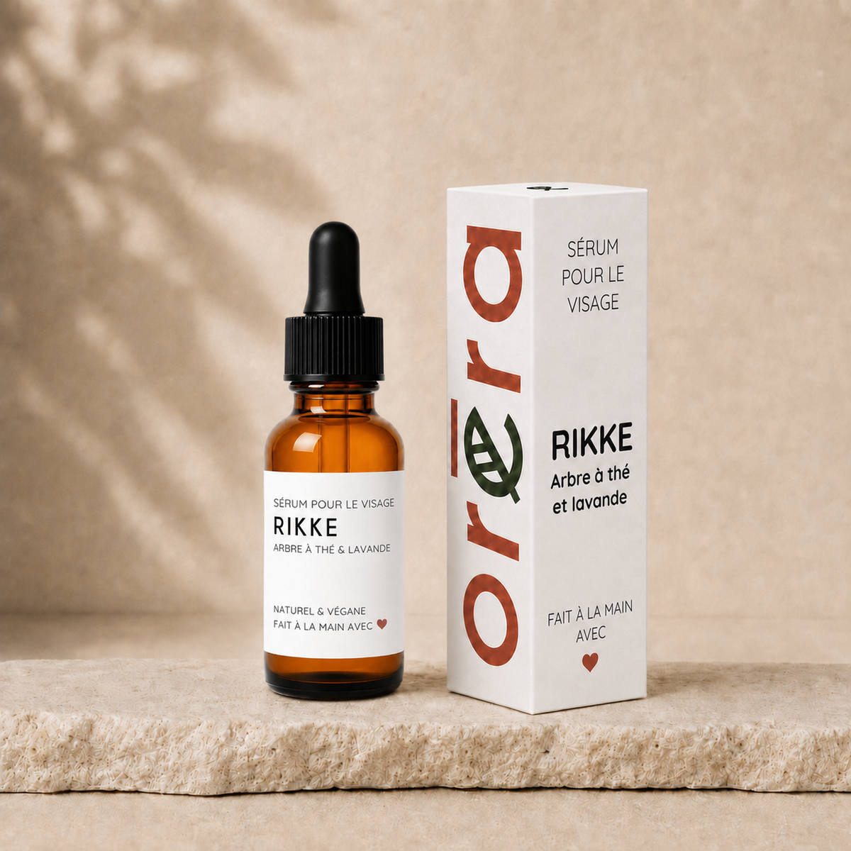 Sérum visage RIKKE en bouteille en verre ambré avec pipette et boîte blanche minimaliste, texte orange et noir.