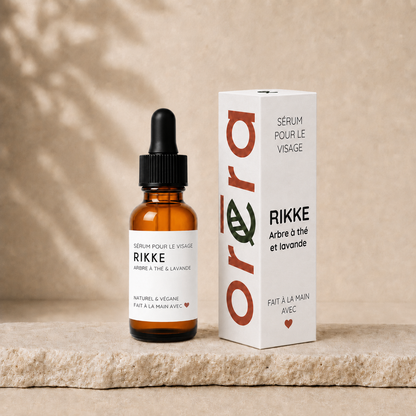 Sérum visage RIKKE en bouteille en verre ambré avec pipette et boîte blanche minimaliste, texte orange et noir.