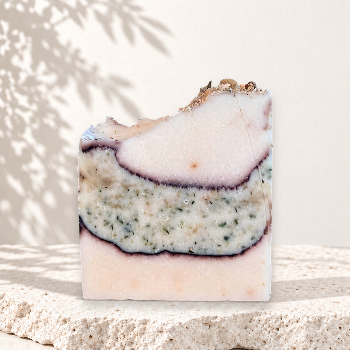 Savon artisanal beige avec couches texturées vertes et violettes, exfoliant naturel au lait de chèvre.