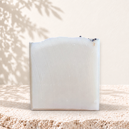Savon carré blanc ivoire avec pétales de lavande sur le dessus, texture lisse, naturel et artisanal.