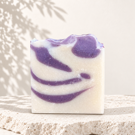 Savon carré blanc avec marbrures violettes, texture artisanale, fini légèrement ondulé, naturel et écologique.
