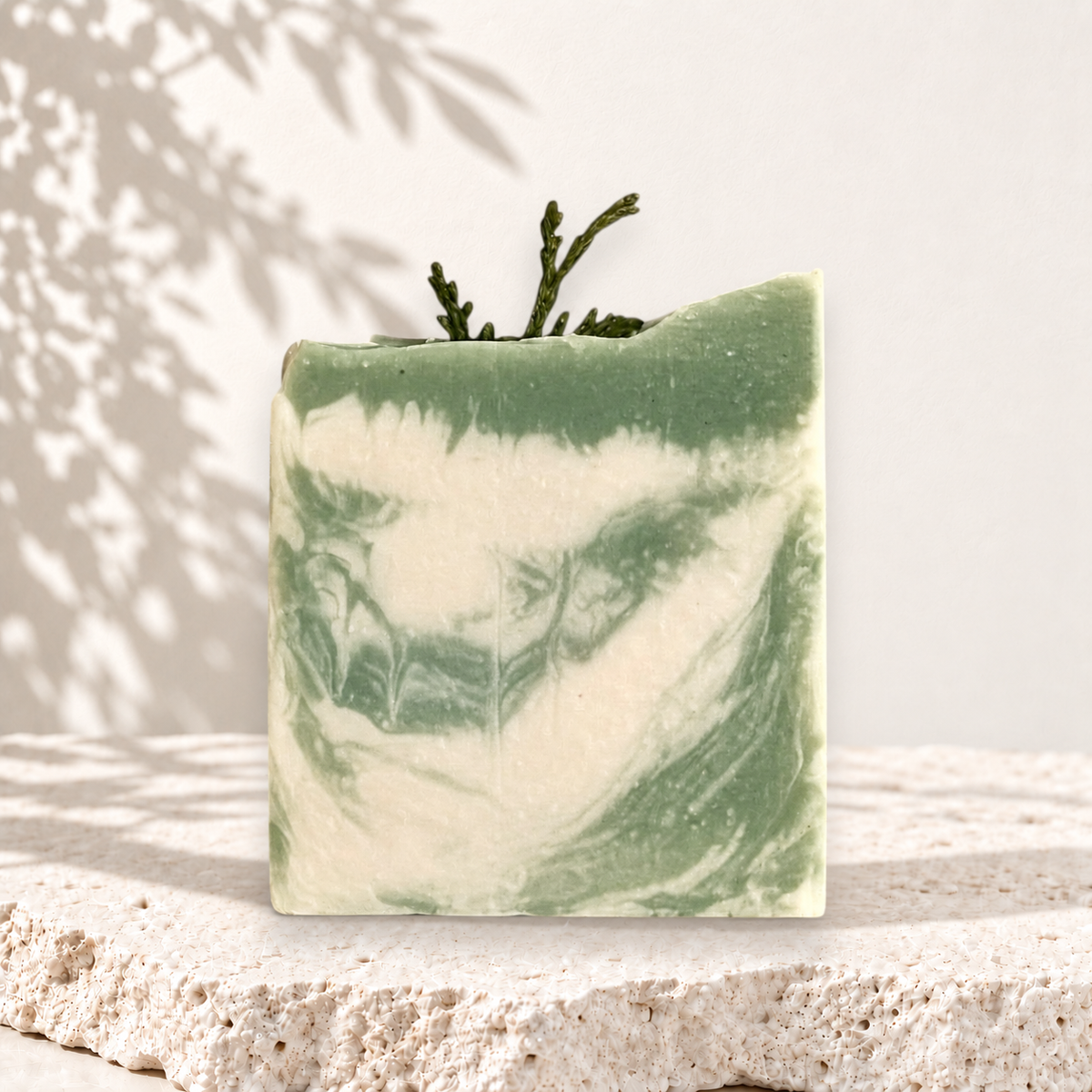 Savon carré vert et blanc marbré au lait de chèvre avec branche décorative, style artisanal.