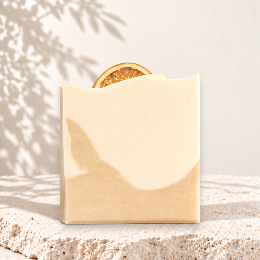 Savon beige naturel carré avec tranche d’orange séchée intégrée, texture lisse.