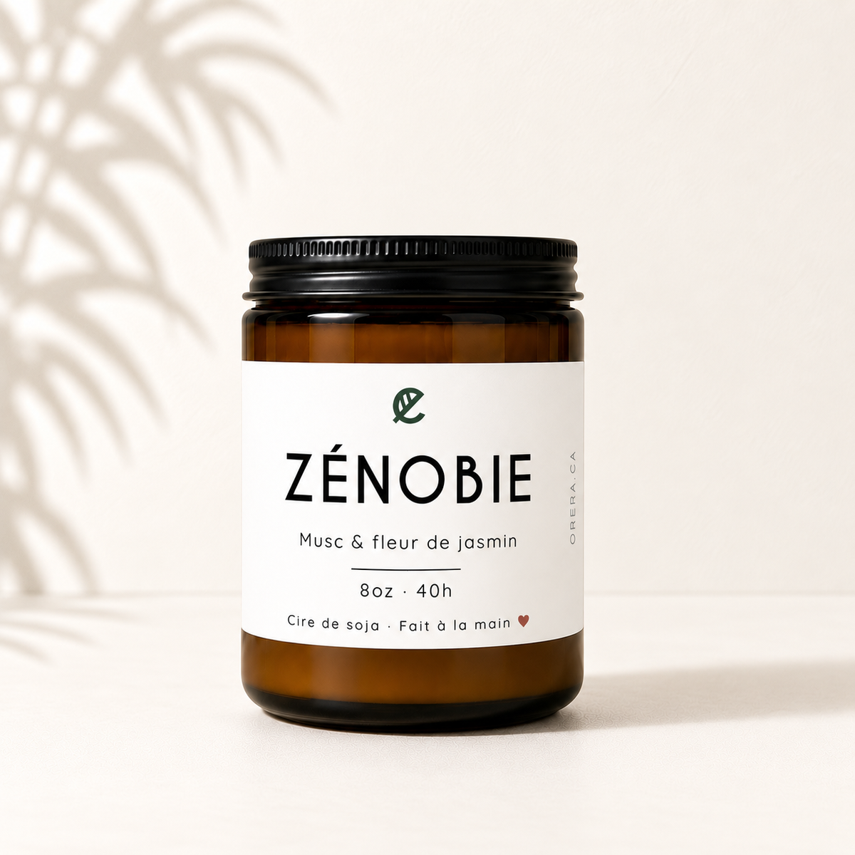 Bougie en verre ambré à couvercle noir avec étiquette blanche, parfum musc et jasmin.